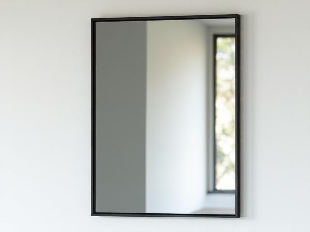 Espejo de pared con marco de metal negro de diseño minimalista, presentando formas cuadradas que se entrelazan creando un efecto visual moderno.